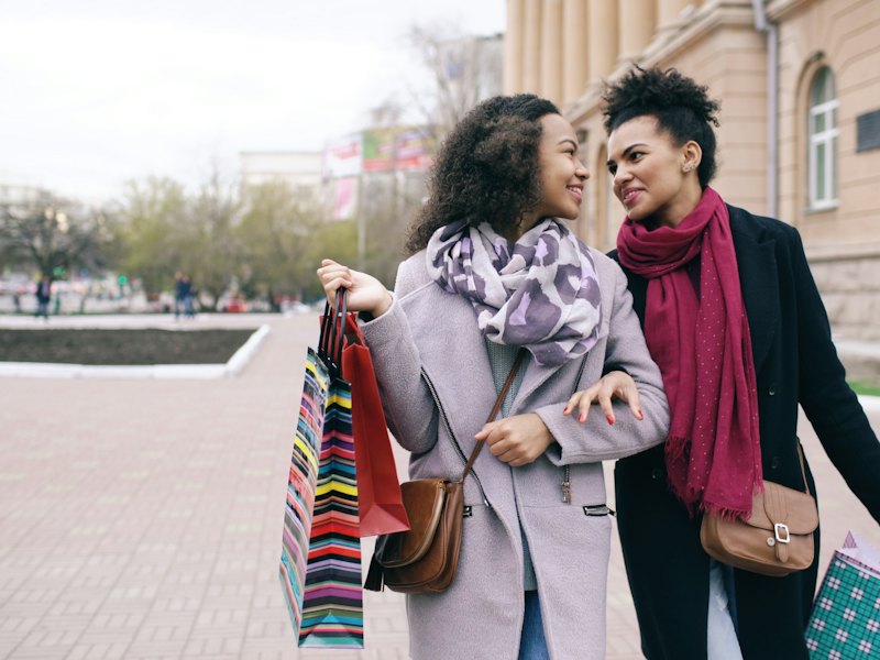 Two friends walking arm in arm after shopping